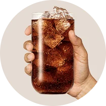 Ręka trzymająca szklankę Pepsi Mango Zero Cukru z lodem.